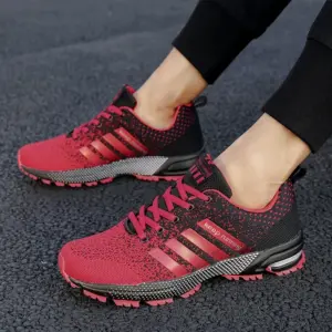 A person wearing 2023 New Men's and Women's Running Shoes Breathable Outdoor Mountaineers Light Sports Shoes Comfortable Training Shoes on a pavement.
